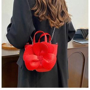 Detail of red PU crossbody bag featuring a large 3D flower and metallic chain strap