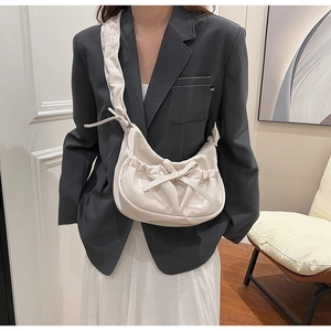 Detail of creamy white PU leather crossbody bag featuring bow tie and ruffled strap
