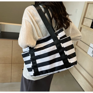 Detail view of large striped tote bag with wide shoulder strap and side pocket
