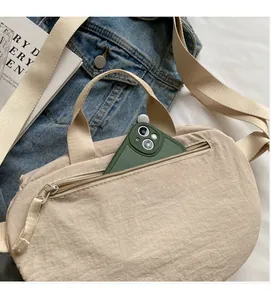 Beige nylon crossbody bag with large front zipper pocket and adjustable wide strap