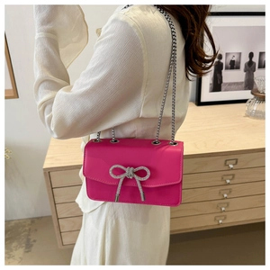 Detail of hot pink PU handbag with sparkling silver rhinestone bow and chain strap