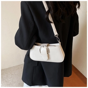 Detail of minimalist beige PU leather crossbody bag with silver horseshoe buckle on a model