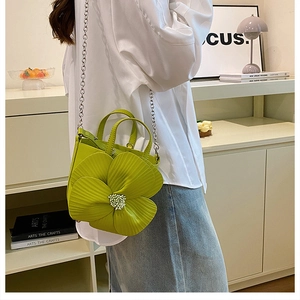 Detail view of a green PU crossbody bag featuring a large 3D floral accent and chain strap