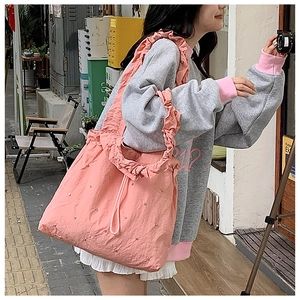 Lifestyle view of a pink pleated tote bag featuring ruffled straps and rhinestone details