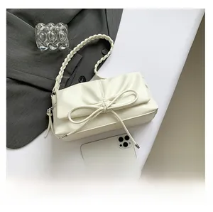 Detail view of cream PU crossbody bag featuring a pleated bow design and woven shoulder strap