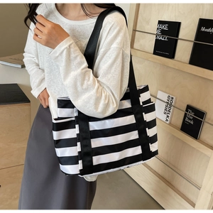 Detail view of striped tote bag with wide nylon strap and functional side pocket