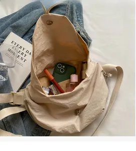 Detail showing spacious interior of beige canvas crossbody bag with daily essentials