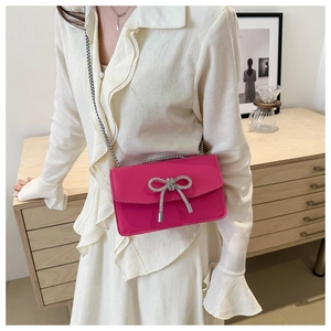 Detail of rose red PU leather crossbody bag with sparkling silver rhinestone bow decoration