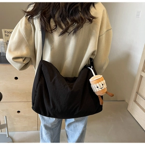 Detail of high-capacity black crossbody bag with a cute plush coffee cup charm
