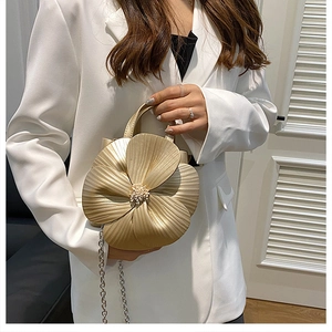 Detail of creative gold flower handbag with pearl center on a white suit jacket