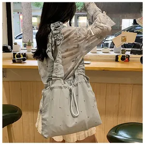 Close-up of light blue nylon ruffled shoulder bag with silver studs and drawstring