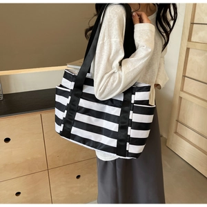 Detail of black and white striped tote bag showing durable fabric and side pocket