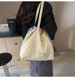 Beige canvas crossbody bag with purple drawstring and 'My Sunday' print shown on model