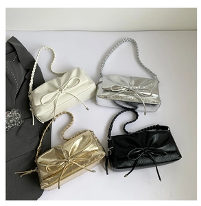 Flat lay of four PU leather handbags in cream, silver, gold, and black with bow details