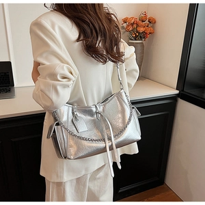 Silver metallic wrinkled tote bag with chain strap shown on model in minimal interior