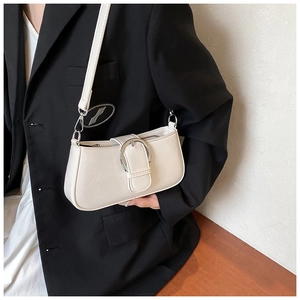 Detail of a creamy white PU leather crossbody bag featuring a large silver metal buckle