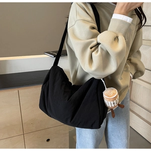 Minimalist black crescent crossbody bag shown on model with plush coffee cup charm