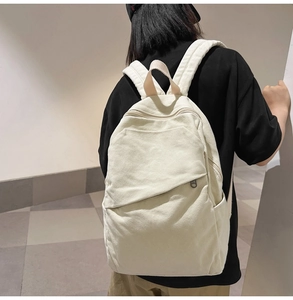 Detail of minimalist cream canvas backpack with asymmetrical front zipper and side pocket