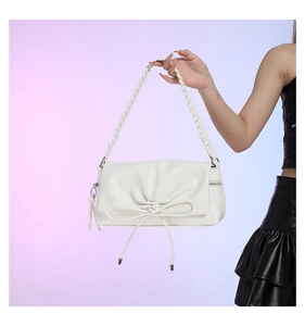 Detail of white PU leather handbag with elegant bow decoration and woven handle design