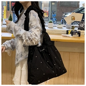 Detail of black nylon tote bag with silver studs and pleated shoulder strap design