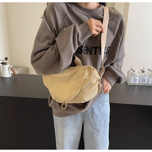 Detail of minimalist beige nylon crescent crossbody bag with pleated design and wide strap