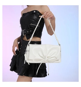 Close-up of white PU handbag featuring a large bow detail and braided shoulder strap