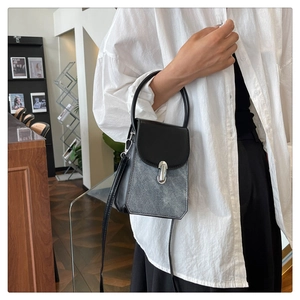Detail view of a vintage PU leather and denim patchwork handbag with a round handle
