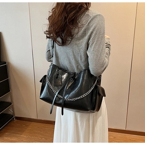 Close-up of black PU leather tote bag with stylish metal chain and long tassel charm