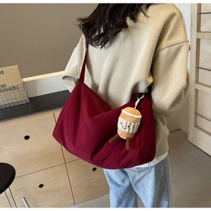 Detail of burgundy canvas crossbody bag with coffee cup charm on wide strap