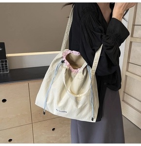 Detail of off-white canvas tote bag with drawstring closure and My Sunday text print