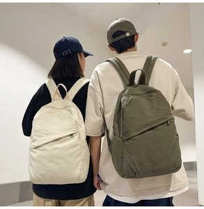 Minimalist canvas backpacks in white and green shown being worn on backs for size scale