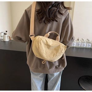 Detailed view of beige crossbody bag showing natural crinkled fabric texture and strap