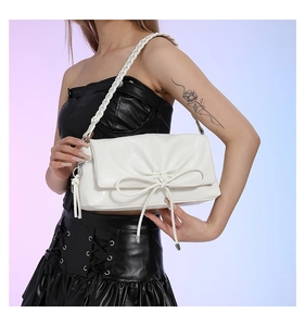 Detail of white PU leather shoulder bag featuring pleats, bow accent and woven strap
