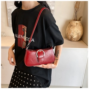 Detail of red glossy PU leather shoulder bag with bold silver round buckle decoration