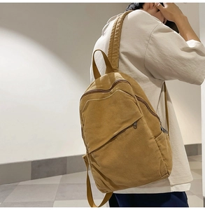 Side view of model wearing a large khaki canvas backpack with minimalist vintage design