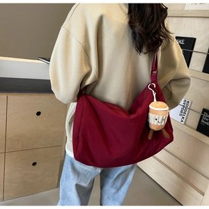 Detail of burgundy hobo bag with nylon fabric and coffee cup plush charm accessory