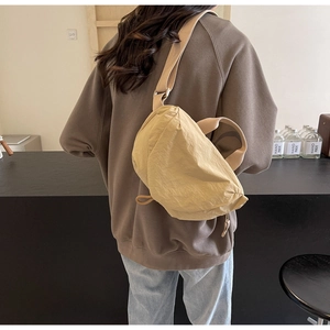 Close-up of beige nylon crossbody bag with drawstring detail on a model's back