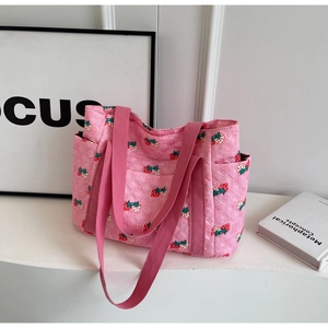 Pink quilted tote bag with strawberry prints and sturdy handles in a minimalist setting