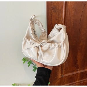 Chic cream-colored pleated PU leather handbag with a bow detail and minimalist half-moon shape