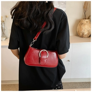 Detail of red PU leather shoulder bag featuring a large silver horseshoe buckle and strap