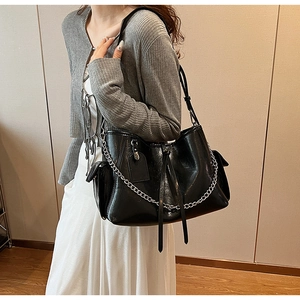 Close-up of black glossy PU leather tote bag with silver chain and drawstring details
