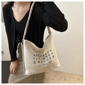 Detail of minimalist cream canvas tote bag with woven texture and black letter printing
