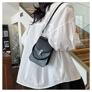 Detail view of a compact PU leather crossbody bag with silver buckle worn by a model