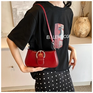 Detail of red textured PU leather bag featuring a large silver horseshoe metal buckle