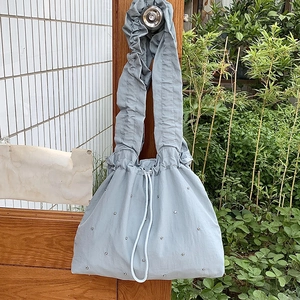 Detail of light blue nylon bag with decorative rhinestones and scrunchie strap design