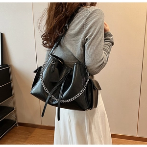 Detail view of large black PU leather crossbody bag with silver chain and functional side pocket