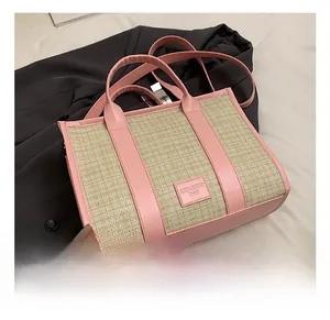 Close-up of woven straw tote bag with pink leather trim and CHAOHUO BAG logo tag