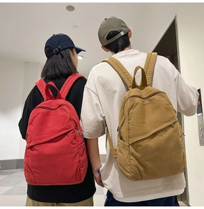 Rear view of model wearing minimalist canvas backpacks in red and khaki colors