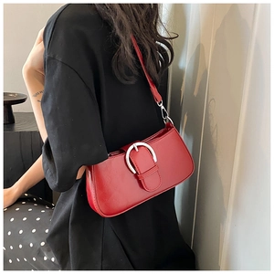 Detail of red PU leather shoulder bag featuring a large silver buckle and zipper closure