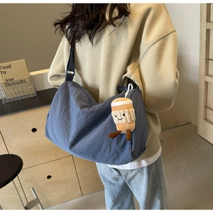 Deep blue nylon crossbody bag with cute coffee cup plush charm shown on a model